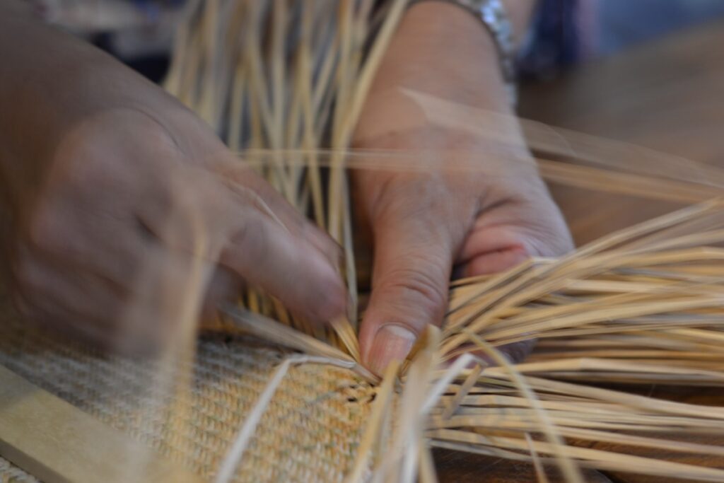 Person weaving straw by hand