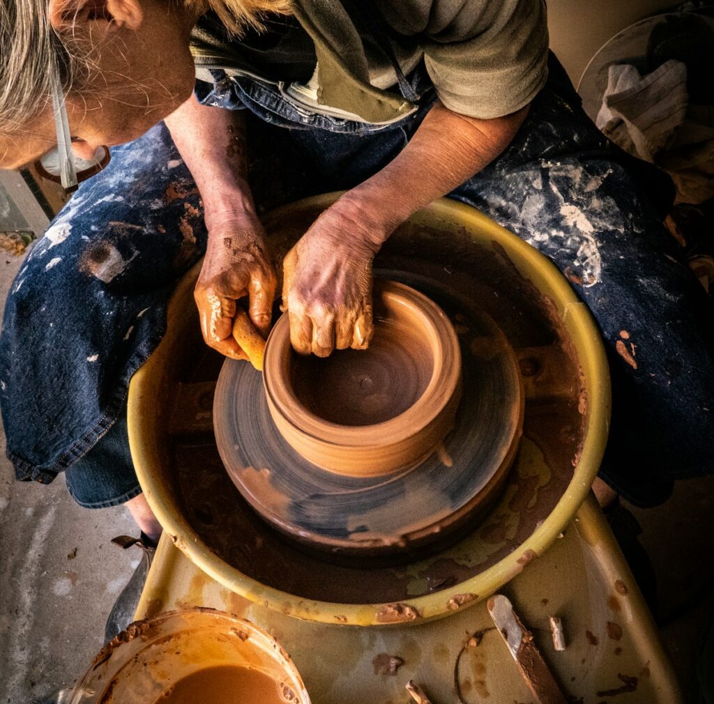 Person hand-shaping a clay pot