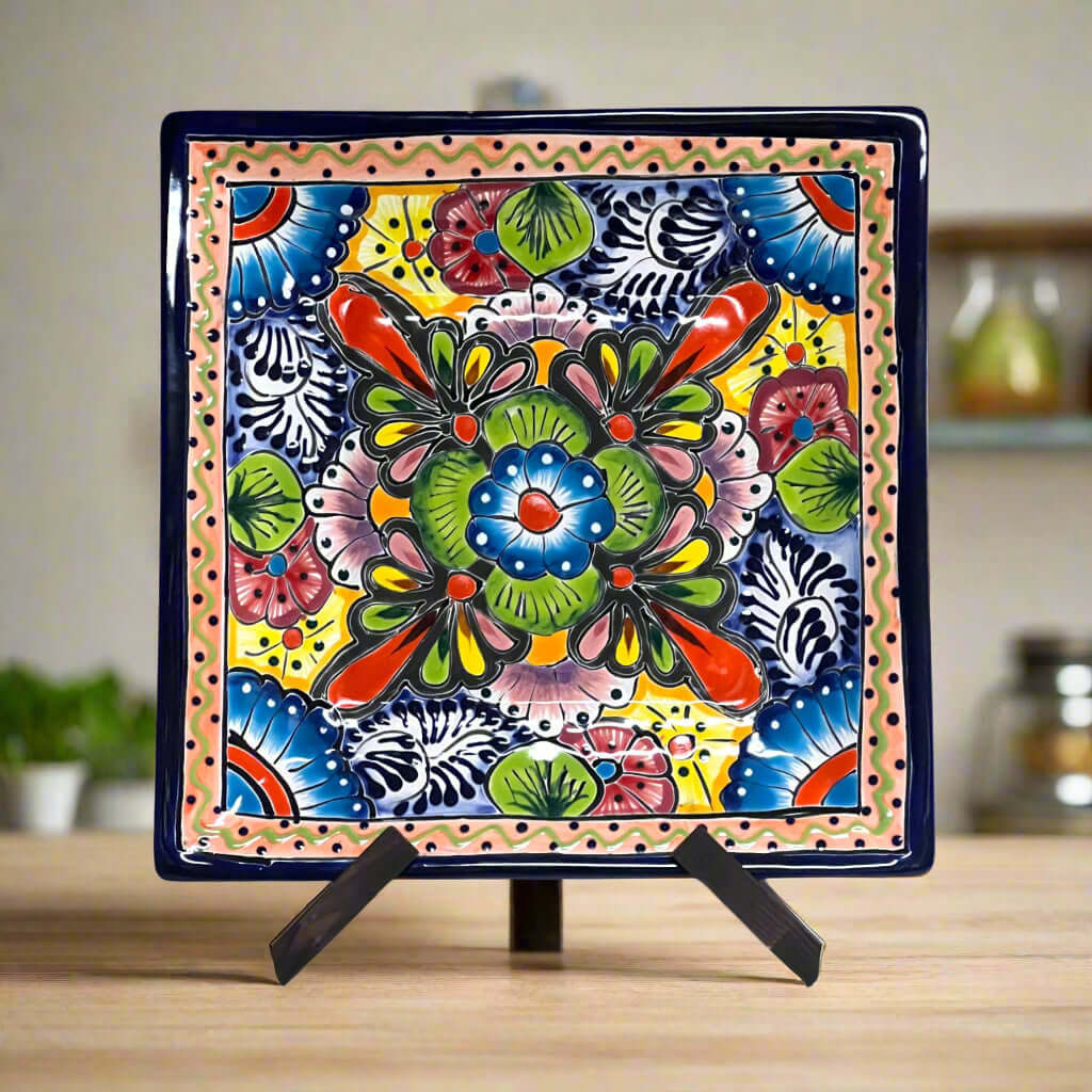 Square hand-painted Talavera-style plate with a bright floral pattern, on a display stand