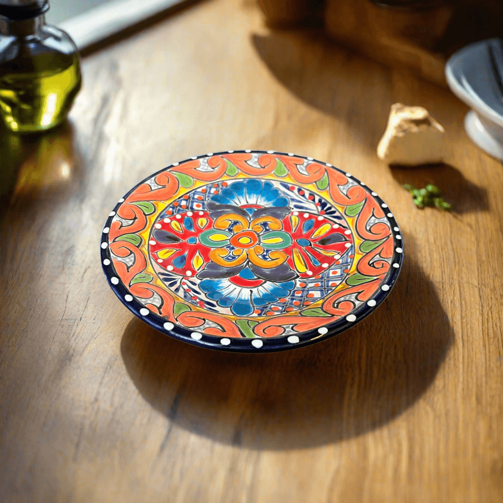 Round hand-painted Talavera-style plate in orange, blue and red, on a wooden table